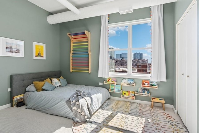 carpeted bedroom featuring a view of city, baseboards, and a closet