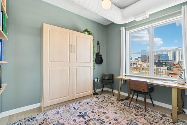 office space featuring baseboards, a view of city, and light wood-style floors