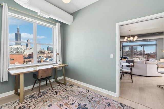 office space featuring a view of city, a notable chandelier, wood finished floors, and baseboards