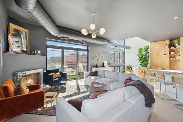 living area featuring a notable chandelier, a lit fireplace, and wood finished floors