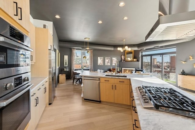 kitchen with light wood finished floors, a sink, light brown cabinetry, stainless steel appliances, and decorative light fixtures