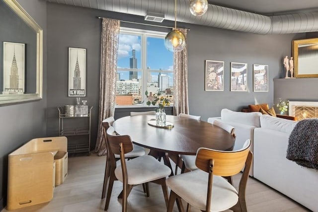 dining room with a view of city and light wood-type flooring