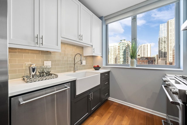 kitchen featuring a view of city, a sink, wood finished floors, stainless steel appliances, and white cabinets