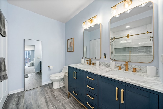 bathroom featuring a sink, wood finish floors, toilet, and a shower with shower door