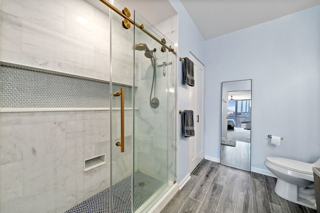 bathroom featuring a shower stall, toilet, baseboards, and wood tiled floor