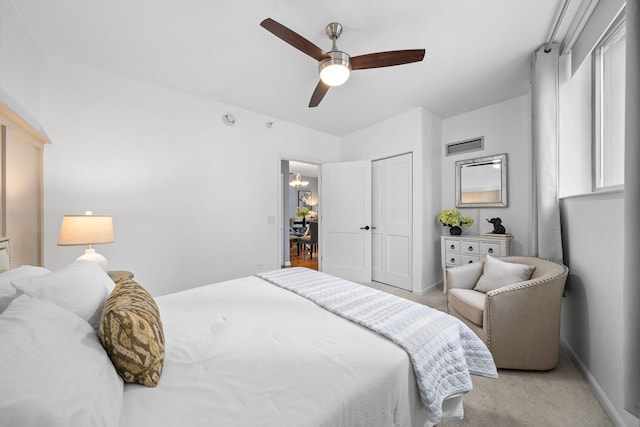 bedroom with visible vents, baseboards, a closet, light carpet, and ceiling fan with notable chandelier