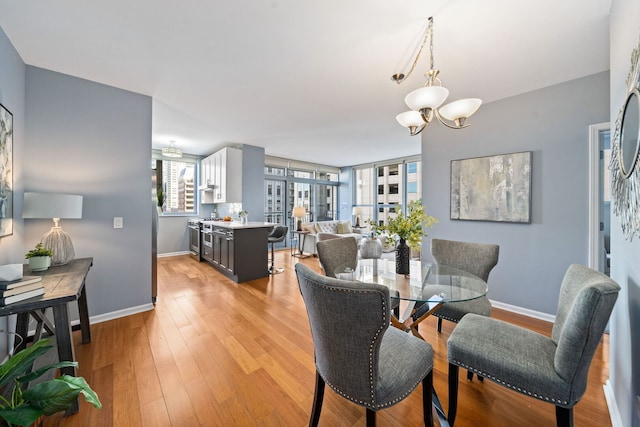 dining area featuring an inviting chandelier, baseboards, and light wood-style floors