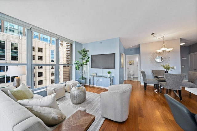 living room featuring a wall of windows, an inviting chandelier, and wood finished floors