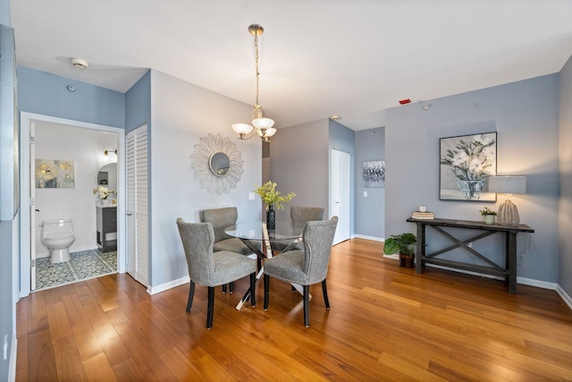 dining room featuring a notable chandelier, baseboards, and hardwood / wood-style floors