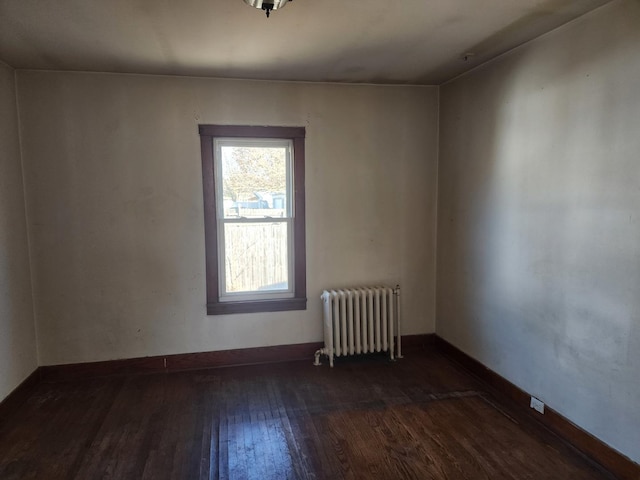 unfurnished room featuring baseboards, radiator heating unit, and hardwood / wood-style flooring