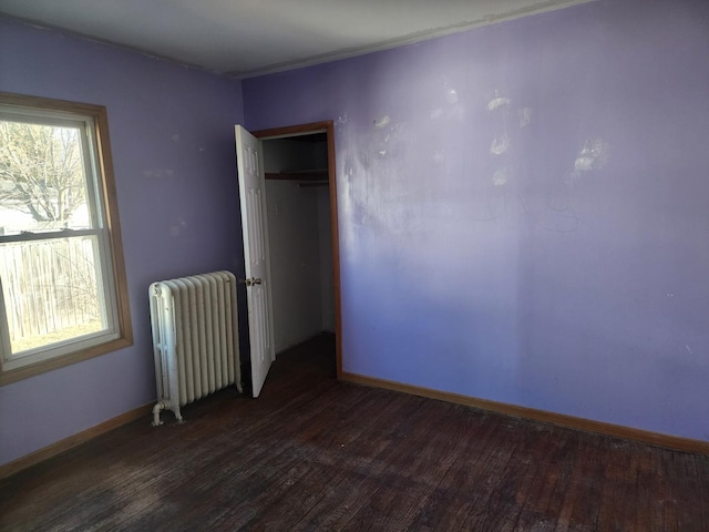 unfurnished room with radiator, baseboards, and hardwood / wood-style flooring