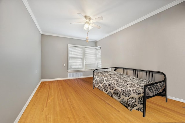 bedroom with visible vents, ornamental molding, a ceiling fan, wood finished floors, and baseboards