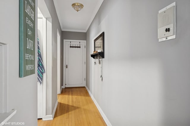 hall with baseboards, crown molding, and light wood finished floors