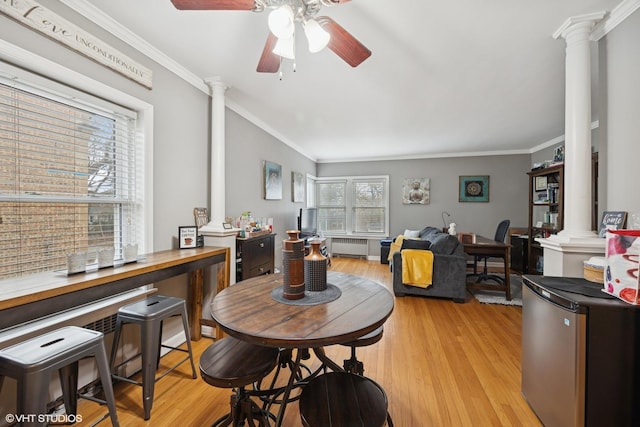 dining area with radiator, light wood-style floors, ornate columns, and ornamental molding