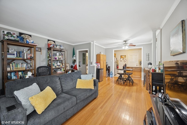 living room with light wood-type flooring, ceiling fan, crown molding, and ornate columns