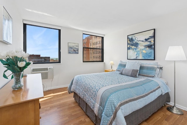 bedroom with light wood-style flooring, a wall mounted AC, and baseboards