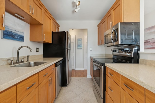 kitchen with light countertops, light tile patterned flooring, appliances with stainless steel finishes, and a sink