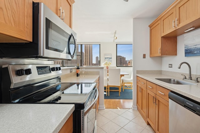 kitchen featuring a city view, light countertops, appliances with stainless steel finishes, light tile patterned flooring, and a sink