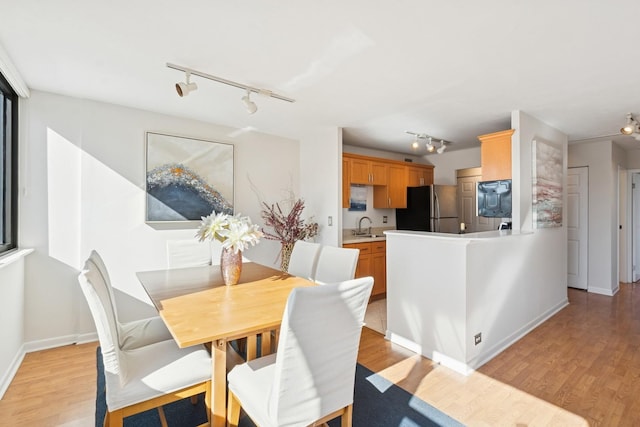 dining space featuring light wood-style flooring and baseboards