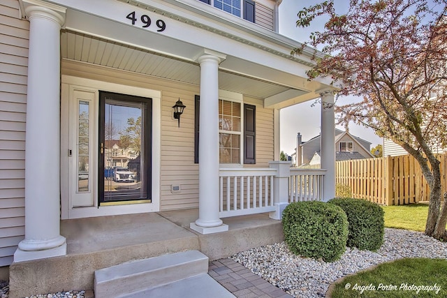 entrance to property with a porch and fence