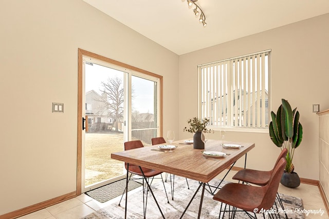 dining room with track lighting, light tile patterned floors, and baseboards