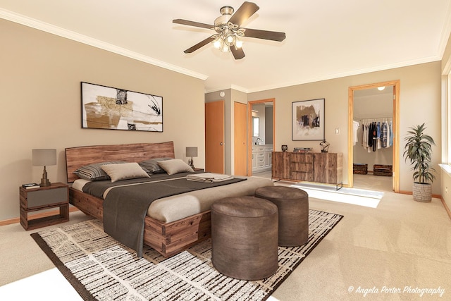 carpeted bedroom with ensuite bathroom, a walk in closet, baseboards, and ornamental molding