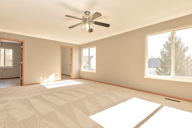 interior space with visible vents, baseboards, light colored carpet, and ornamental molding