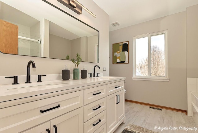 bathroom featuring a sink, visible vents, baseboards, and double vanity