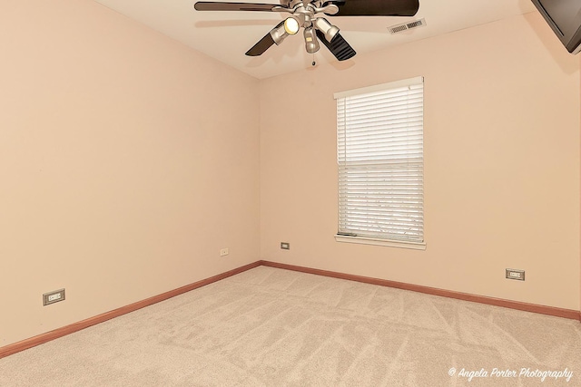 empty room featuring visible vents, light carpet, baseboards, and a ceiling fan