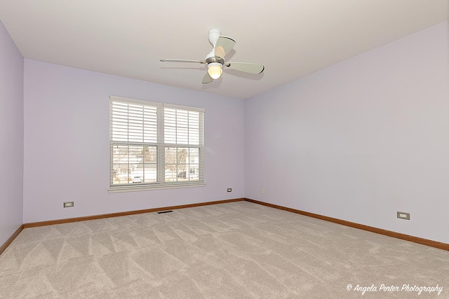 spare room with baseboards, light carpet, visible vents, and a ceiling fan