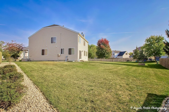 back of house featuring a yard and fence