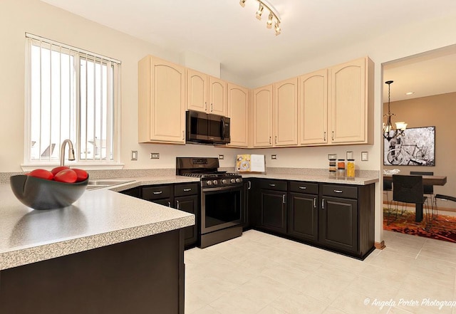 kitchen featuring light countertops, cream cabinets, gas stove, and a chandelier