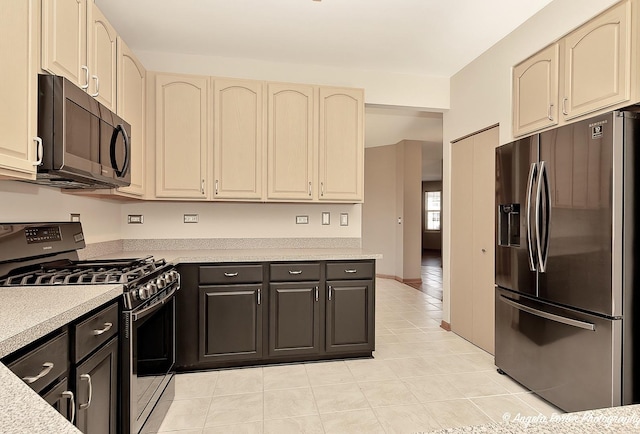 kitchen with light tile patterned floors, baseboards, light countertops, appliances with stainless steel finishes, and cream cabinets