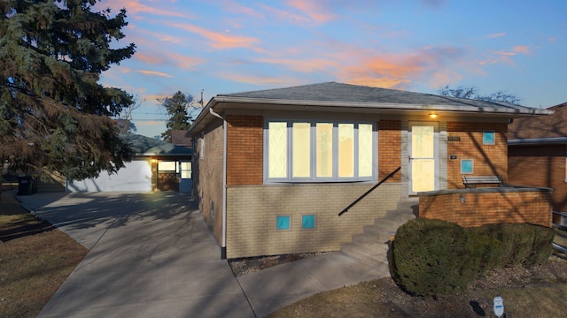 view of front of house with a garage, an outbuilding, brick siding, and driveway