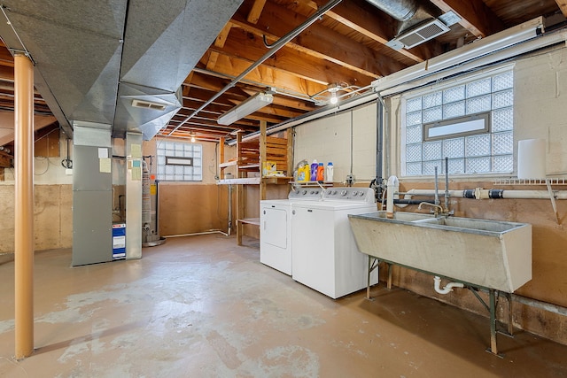 below grade area featuring heating unit, washing machine and dryer, and a sink