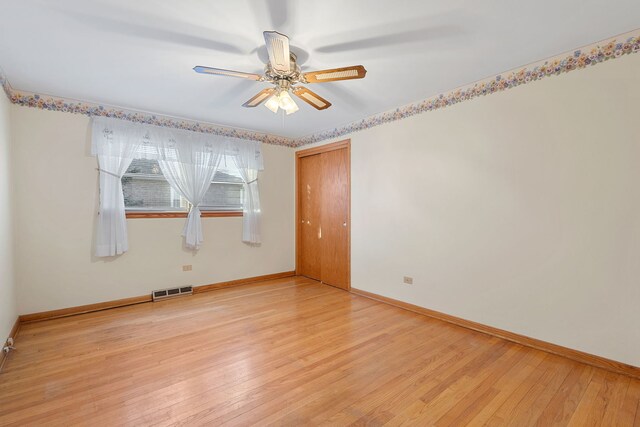 spare room featuring a ceiling fan, baseboards, visible vents, and light wood finished floors