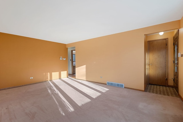 carpeted spare room featuring visible vents and baseboards