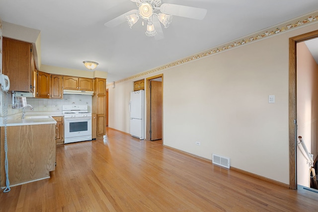 kitchen featuring visible vents, under cabinet range hood, light wood-type flooring, white appliances, and a ceiling fan