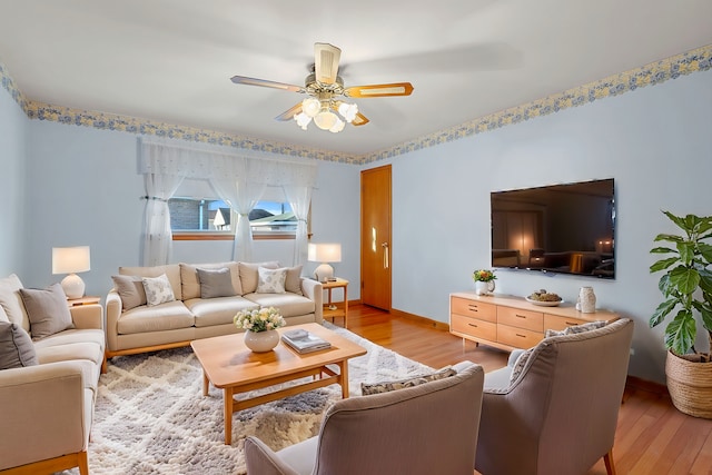 living room featuring baseboards, ceiling fan, and light wood finished floors