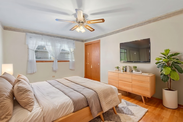 bedroom featuring a closet, a ceiling fan, crown molding, and light wood-style floors