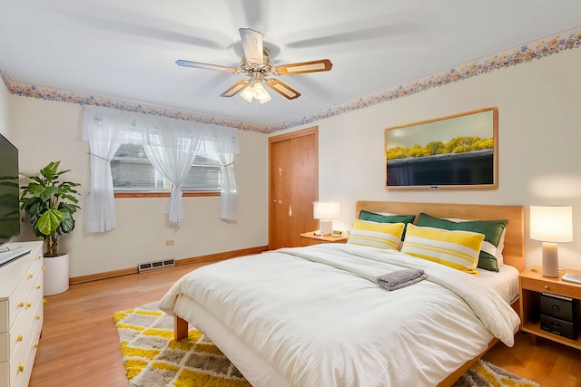 bedroom featuring a ceiling fan, visible vents, light wood-type flooring, and baseboards