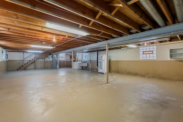 unfinished basement with a sink, heating unit, and stairs