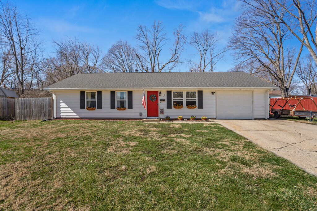 ranch-style house featuring a front yard, driveway, fence, and an attached garage
