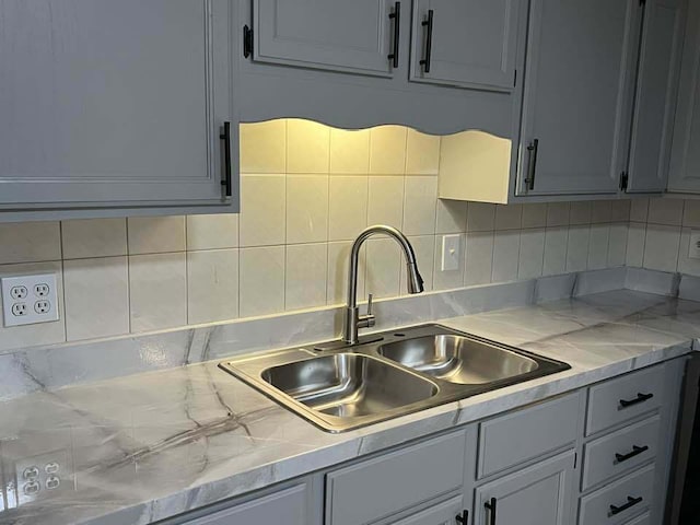 kitchen featuring decorative backsplash, light countertops, and a sink