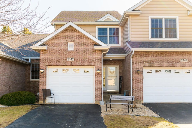 traditional home featuring aphalt driveway and brick siding