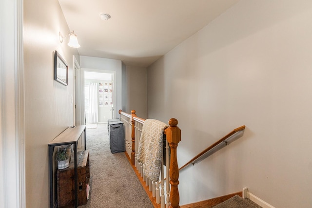 corridor featuring baseboards, an upstairs landing, and carpet flooring