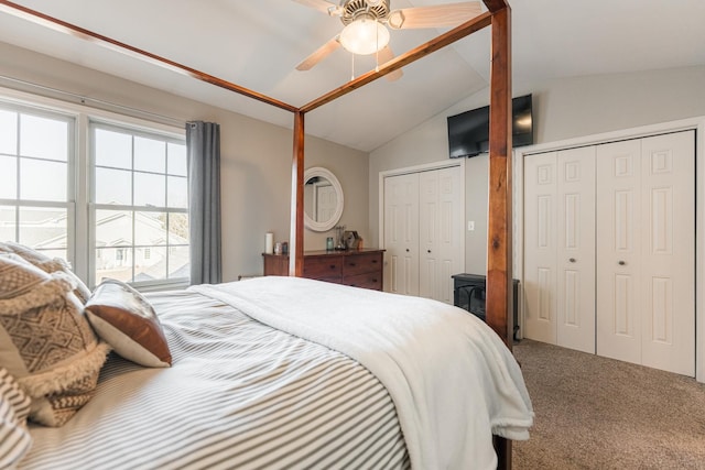 carpeted bedroom featuring multiple closets, ceiling fan, and vaulted ceiling