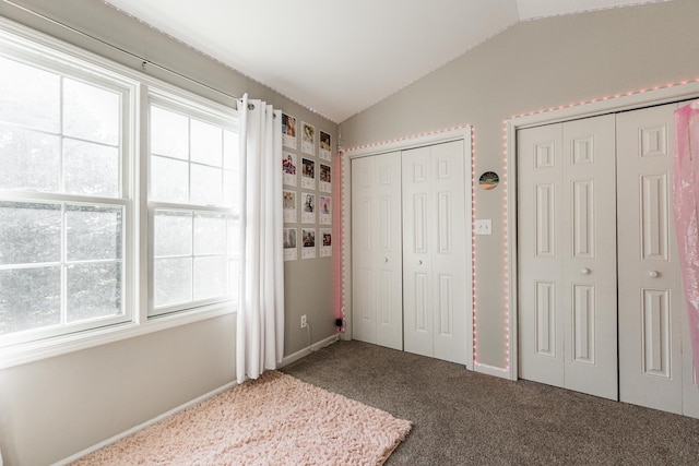 unfurnished bedroom featuring lofted ceiling, multiple closets, and carpet floors