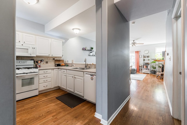 kitchen featuring a sink, decorative backsplash, white appliances, and light wood-style floors