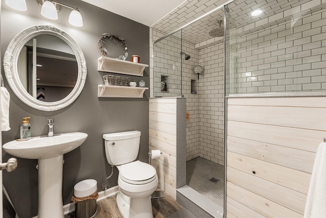 bathroom featuring baseboards, toilet, wood finished floors, and a shower stall